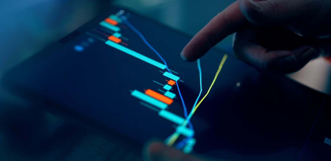 Close-up of a finger pointing at a stock market chart on a tablet screen